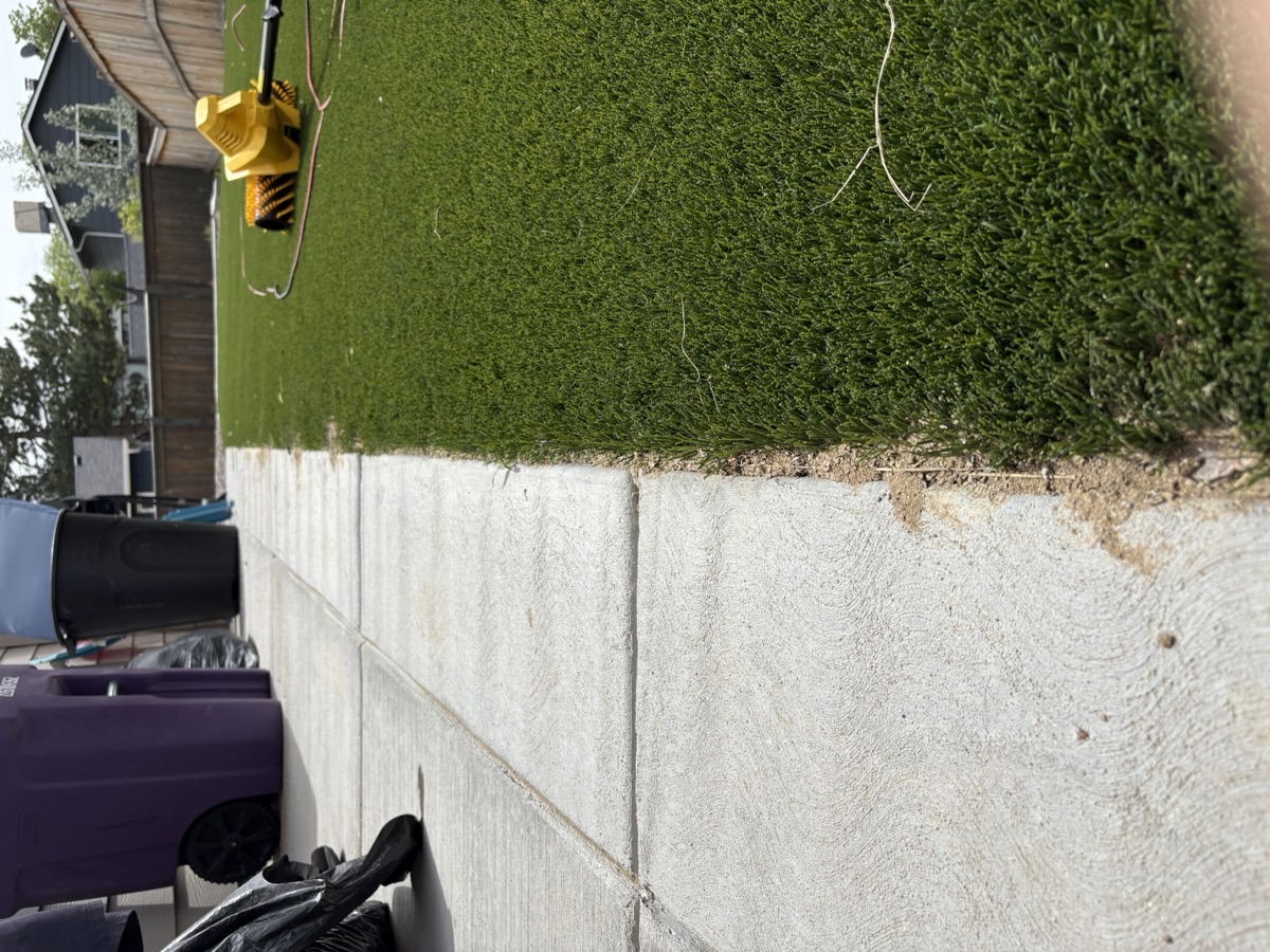 Power broom equipment grooming artificial turf along a patio edge in Colorado
